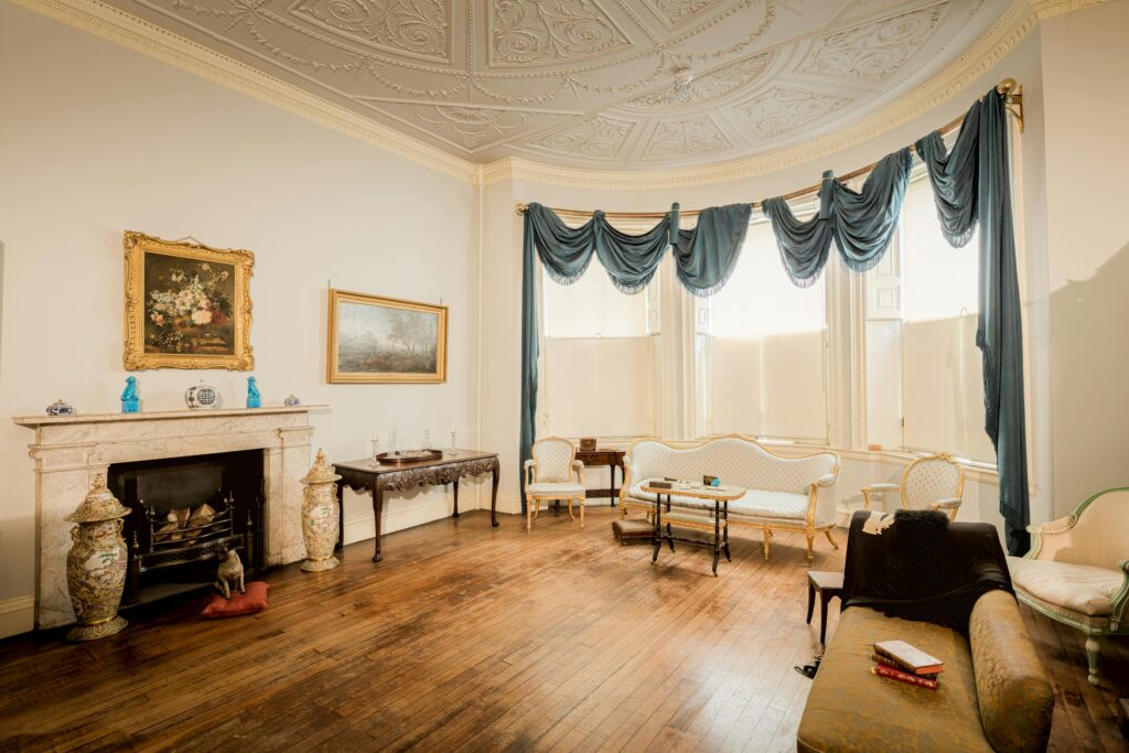 Classic English drawing room with vintage decor, ornate ceiling, and antique furnishings.